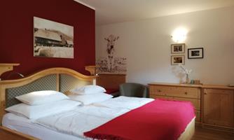 A cozy bedroom with a large bed and red accents. The walls are adorned with pictures and decorations that create an inviting atmosphere.