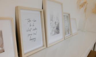 A simple shelf with several framed pictures. One of them contains the inscription: "Take time to do what makes your soul happy".
