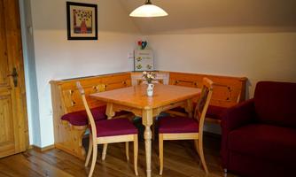 A cozy dining area with a wooden table and chairs. The walls are painted in a light color, and the room has a warm, inviting atmosphere.