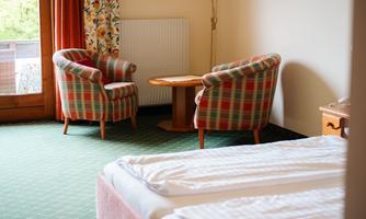 A cozy room with two comfortable armchairs and a table. The walls are painted in warm colors and there is access to the balcony.