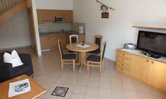 A cozy apartment with a modern kitchen and a dining area. The living room features a television and a comfortable couch.