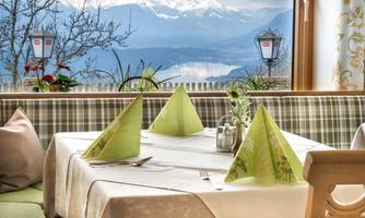 An elegantly set table in a restaurant with a view of the mountains. The windows showcase a beautiful view of the snow-capped peaks and the clear sky.