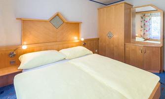 A cozy bedroom with a double bed and bright yellow bed sheets. The room has wooden furniture and a window with curtains.