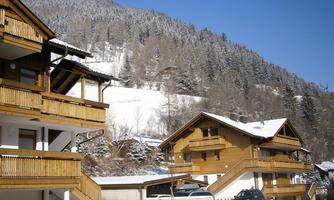 A beautiful winter destination with wooden houses and snow-covered mountains. The clear, cold air completes the idyllic scenery.