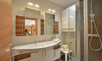 A modern bathroom with a large shower cubicle and an elegant sink. Bright tiles and wood accents create a pleasant atmosphere.