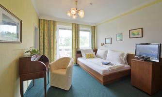 A bright room with a single bed and an armchair. Large windows provide plenty of daylight and a cozy atmosphere.