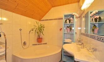 A modern bathroom with a bathtub and a sink. On the wall are plants and decorative shelves with towels and orchids.