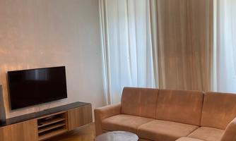 A modern living room with a comfortable sofa and a round table. The light curtains and the decorative lamp create a cozy atmosphere.