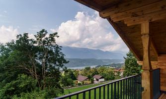 A beautiful view from a terrace over green meadows and snow-capped mountains. The clouds in the blue sky give the scene a peaceful atmosphere.