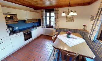 A cozy kitchen with modern appliances and a dining table. Large windows let in plenty of light and create an inviting atmosphere.