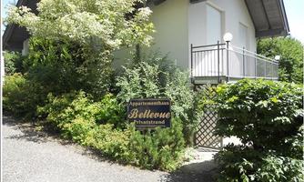 A well-maintained apartment building named "Bellevue" in a green environment. The facade is surrounded by plants, and there is a small balcony.