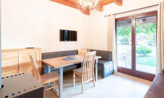 An inviting dining area with a table, chairs, and a sofa. Large windows offer a view of the garden.