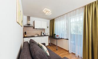 A modern kitchen with a cozy sofa.  
Large windows let in plenty of light and the decor is simple and inviting.