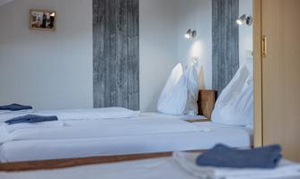 A simple room with two beds and modern light sources. The walls have a bright, cheerful color and a wood look.