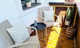 A cozy balcony with two chairs and a small table. Plants and decorative elements create an inviting atmosphere.