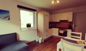A modern kitchen with a cozy living room. The room features bright furniture and plenty of natural light.