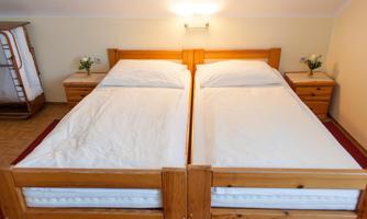 A cozy bedroom with two wooden single beds. There are small flower vases on the nightstands.