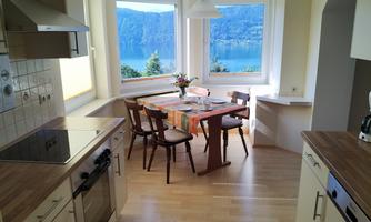 A bright kitchen with modern appliances and a table for four people. Large windows provide a beautiful view of the landscape.