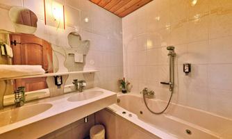 A modern bathroom with two sinks and a bathtub. The walls are tiled and the ceiling is made of wood.