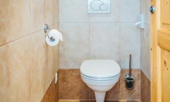 A modern bathroom with a white toilet and gray tiled floor. The walls are in light beige and brown tones.