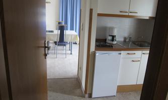 A small kitchen with modern appliances and a view of a dining area. The room is bright and tastefully decorated.