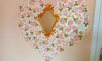 A heart-shaped mirror frame with a floral pattern. The colors are soft and inviting.