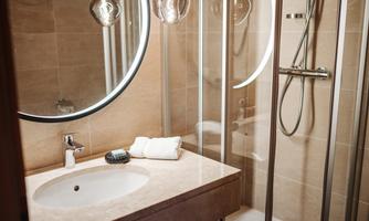 A modern bathroom with a shower and an elegant sink. The lighting creates a cozy atmosphere.