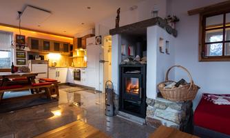 A cozy living room with modern furniture and a fireplace. The kitchen is fully equipped and the space is warm and inviting.