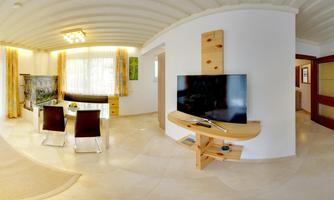 A modern living room with a large TV and a dining area. The walls are light, with large windows and stylish curtains.