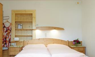 A cozy bedroom with a large wooden double bed. The walls are light and the floor is made of wood, creating a warm atmosphere.