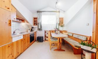 A cozy kitchen with wood paneling and a dining table. Large windows provide plenty of daylight.
