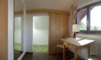 A bright room with a table and a chair. The window offers a view of the green meadow outside.