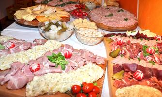 A rich selection of cold cuts and cheese on wooden boards. Accompanied by small snacks and fresh tomatoes, ideal for a festive buffet.