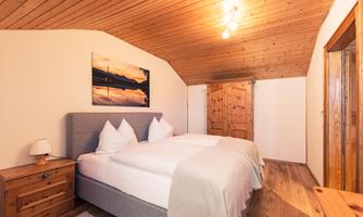 A cozy bedroom with a double bed and wooden ceiling. The atmosphere is warm and inviting, perfect for relaxing overnight stays.