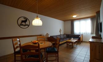 A cozy living space with a table and chairs as well as a couch. A large window provides plenty of daylight.