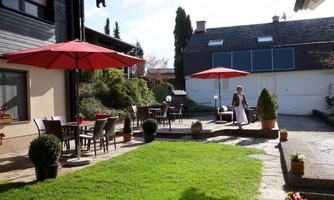 An inviting outdoor area with red parasols and comfortable seating. The lawn is green and well-maintained, perfect for relaxing hours outdoors.
