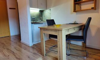A bright kitchen unit with wooden details and modern chairs. The room feels cozy and inviting.