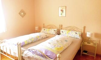 A cozy bedroom with two single beds and colorful bedspreads. The walls are in soft colors, and it is pleasantly bright.