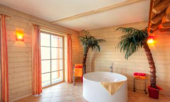 A modern bathroom with a round bathtub and palm trees. The walls are made of wood and the windows let in a lot of light.