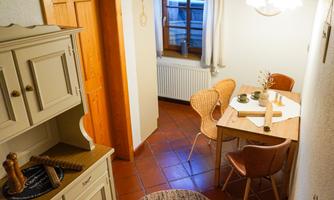 A cozy dining area with a table and round chairs. The warm colors and wooden details create an inviting atmosphere.