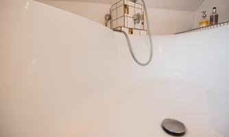An elegant bathtub with a modern faucet. In the background, some bathroom products are visible.