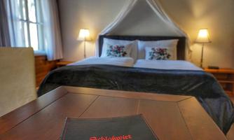 An inviting bedroom with a large bed and cozy bedding. On a table lies a black menu card that elegantly complements the room.