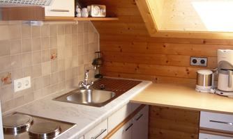 A modern kitchen with wood paneling and a skylight. It is well-equipped with a stove, sink, and a small table.
