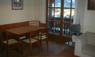 A cozy living space with a table and chairs as well as a sofa. Large windows offer a view of the mountains.