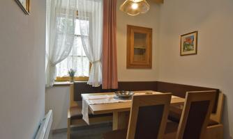 A simply furnished dining area with a wooden table and chairs. The window provides plenty of daylight and a cozy atmosphere.