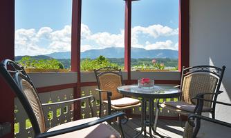 A stylish balcony with a table and chairs. In the background, mountains and a blue sky can be seen.