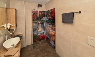 A modern bathroom with tiles in neutral colors. The wall features an impressive motif of a waterfall and red leaves.