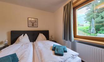 A cozy bedroom with two single beds and fresh towels. From the window, you can see into the green.