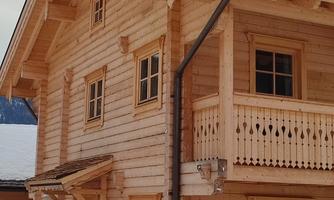 A pretty wooden house with several windows and a balcony. The building has a traditional design and is surrounded by a peaceful environment.