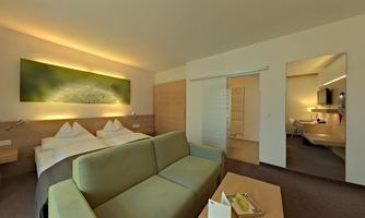 A modern hotel room with a comfortable sofa and two beds. Soft lighting and a calm atmosphere create an inviting space.